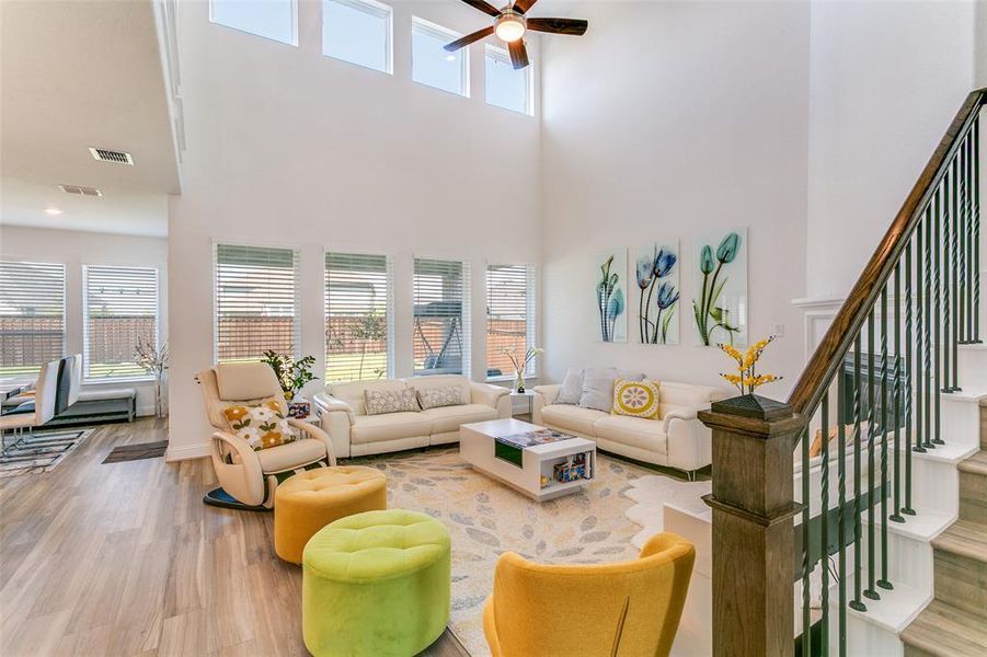 Living room featuring stairway, wood finished floors, a high ceiling, and ceiling fan