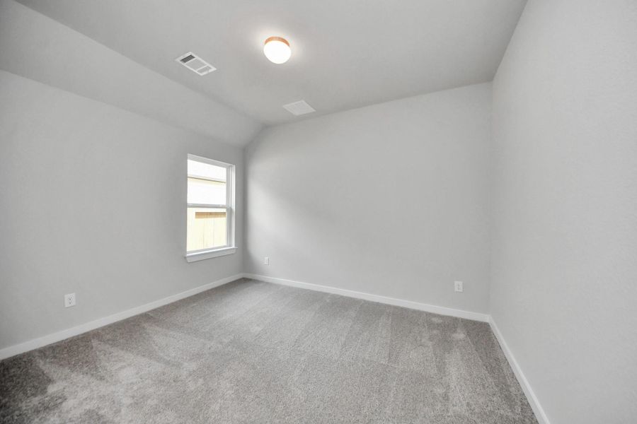 Secondary bedroom features plush carpeting, large windows that let in plenty of natural light, bright paint, and spacious closets. Sample photo of completed home with similar floor plan. Actual colors and selections may vary.
