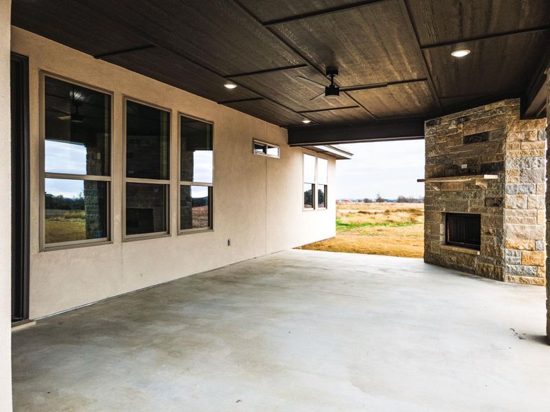 View of patio with an outdoor stone fireplace and a ceiling fan
