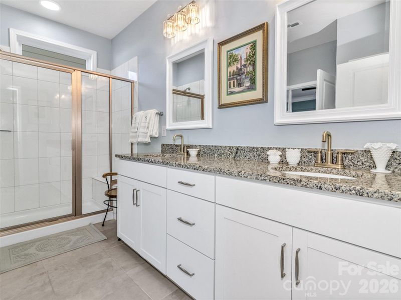 Large primary bath with tiled shower and double vanity.