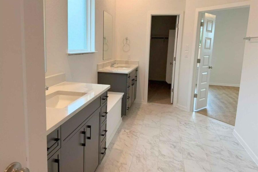 Bathroom with two vanities, light marble finish floors, and a spacious closet