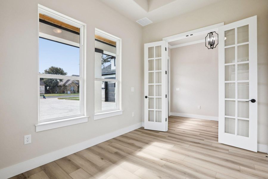 Unfurnished dining area featuring french doors, light wood-style flooring, and a chandelier