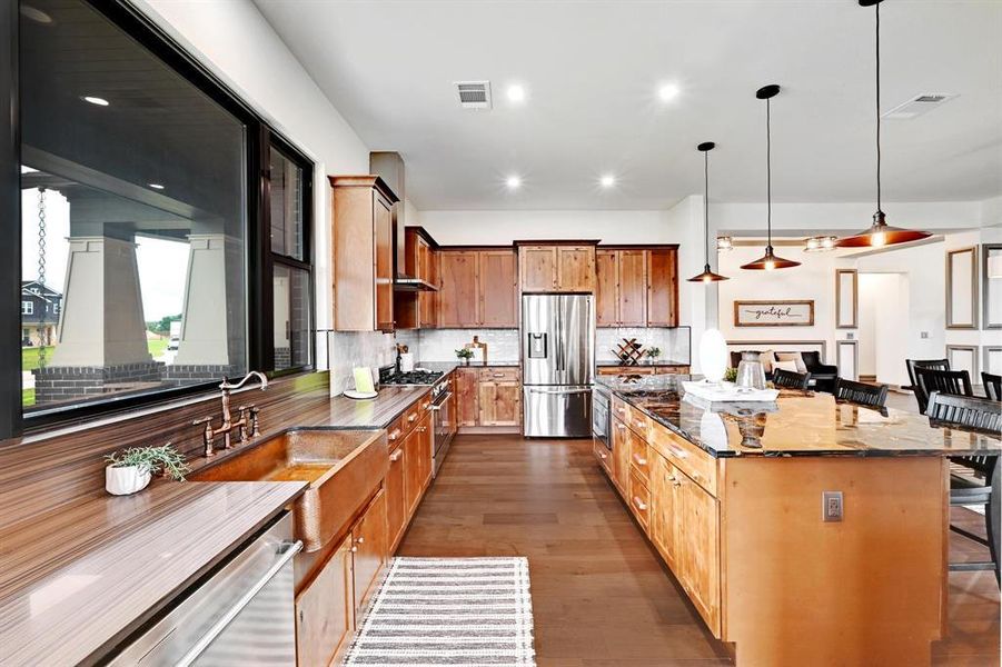 Kitchen featuring a center island, appliances with stainless steel finishes, dark wood-type flooring, a breakfast bar, and pendant lighting
