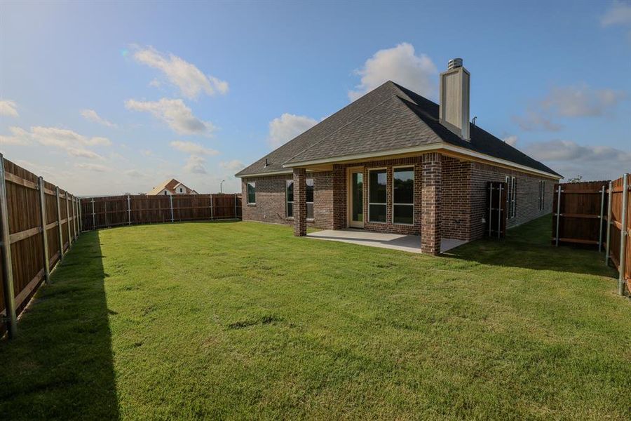 Back of property with brick siding, a shingled roof, a patio area, a fenced backyard, and a chimney Back of property with brick siding, a shingled roof, a patio area, a fenced backyard, and a chimney