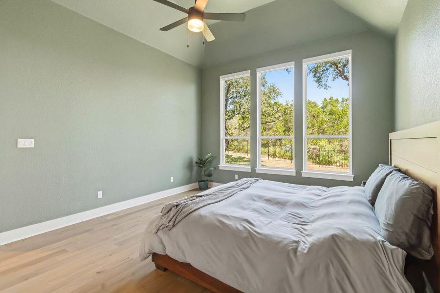 Natural light streams into this serene bedroom, highlighting the smooth wood flooring and vaulted ceilings.