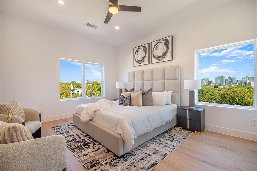 Bedroom with light wood-style flooring, recessed lighting, ceiling fan, and a skyline view Bedroom with light wood-style flooring, recessed lighting, ceiling fan, and a skyline view