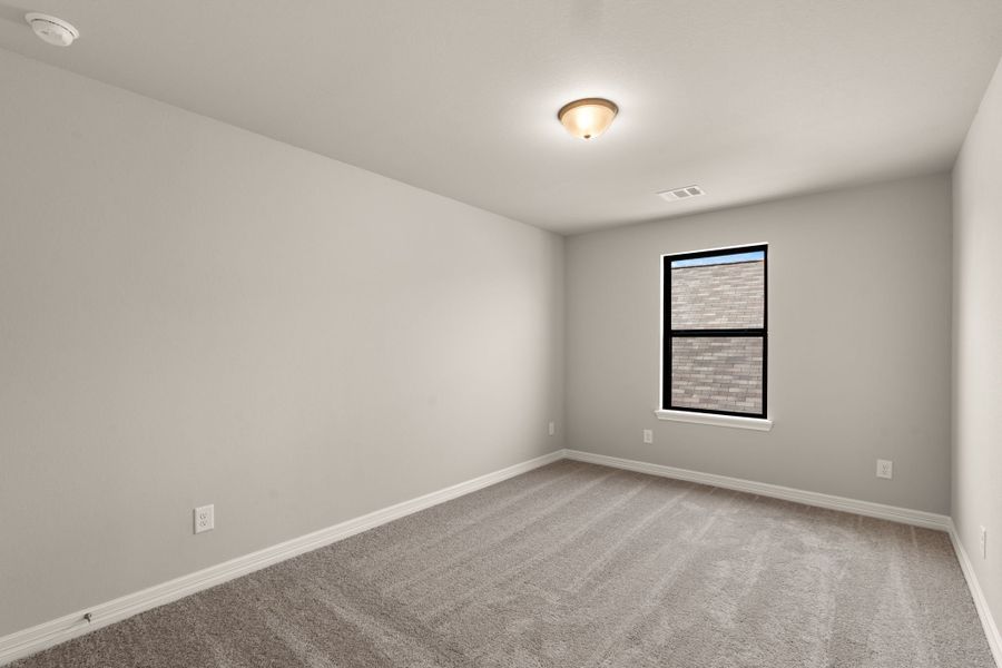 The third bedroom features plush carpet, neutral paint and a large window.