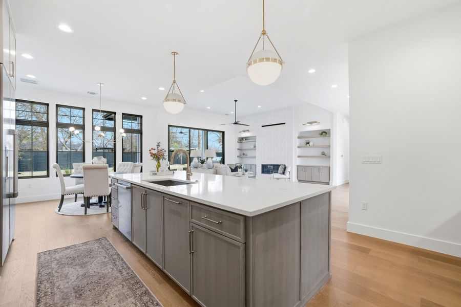 Kitchen featuring pendant lighting, light wood-style flooring, open floor plan, and an island with sink