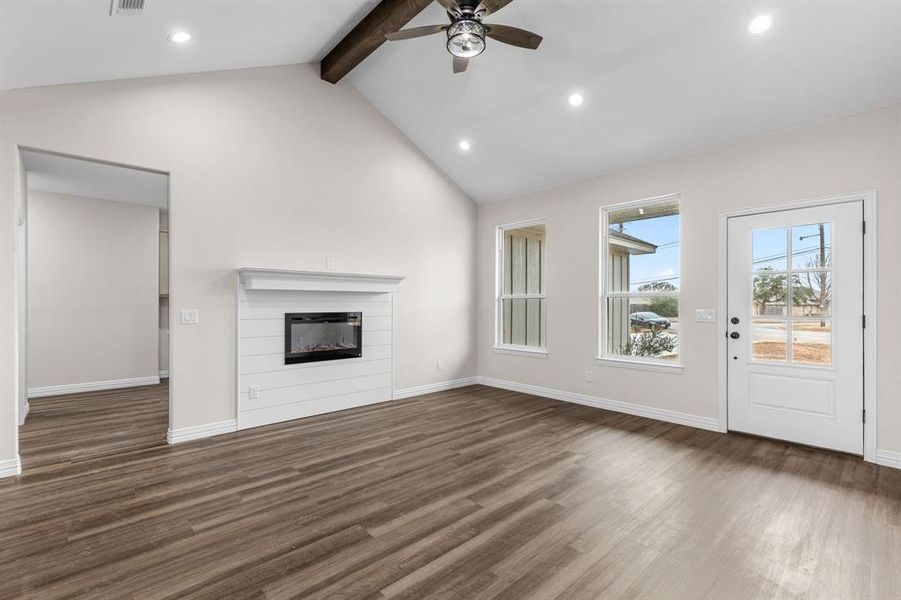 Unfurnished living room featuring ceiling fan, high vaulted ceiling, dark hardwood / wood-style floors, and beam ceiling Unfurnished living room featuring ceiling fan, high vaulted ceiling, dark hardwood / wood-style floors, and beam ceiling
