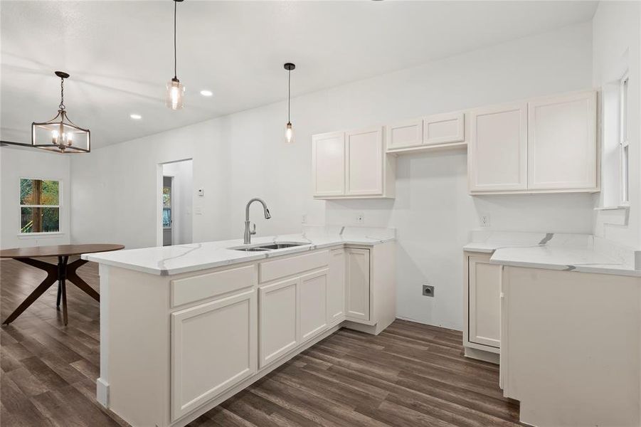 Kitchen featuring kitchen peninsula, decorative light fixtures, an inviting chandelier, dark hardwood / wood-style floors, and white cabinetry