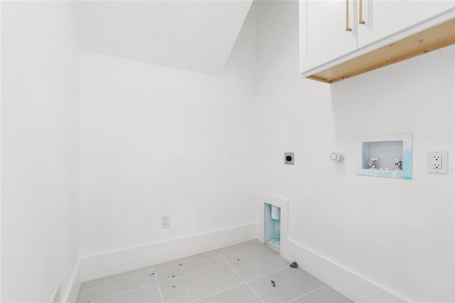 Laundry area featuring gas dryer hookup, tile patterned flooring, cabinet space, washer hookup, and electric dryer hookup Laundry area featuring gas dryer hookup, tile patterned flooring, cabinet space, washer hookup, and electric dryer hookup