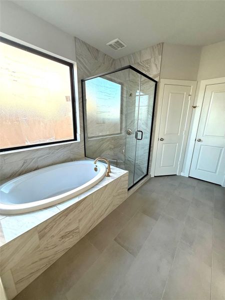 A sleek glass-enclosed shower alongside a deep soaking tub creates a balance of modern design and relaxation in this main bathroom. A sleek glass-enclosed shower alongside a deep soaking tub creates a balance of modern design and relaxation in this main bathroom.