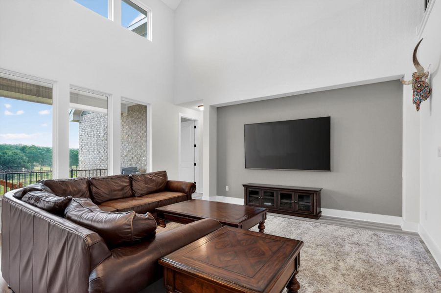 Vaulted ceiling living area featuring expansive windows, recessed lighting, and a stone exterior balcony Vaulted ceiling living area featuring expansive windows, recessed lighting, and a stone exterior balcony