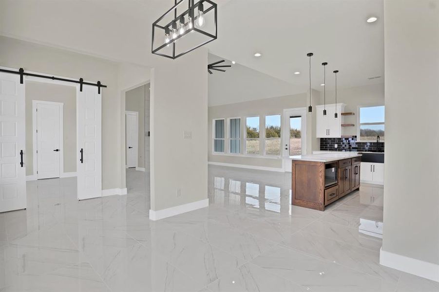 Kitchen featuring white cabinetry, hanging light fixtures, tasteful backsplash, a kitchen island, and a barn door