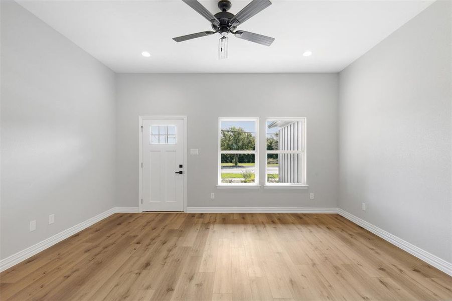 Kitchen with stainless steel electric range, backsplash, white cabinets, and light hardwood / wood-style flooring