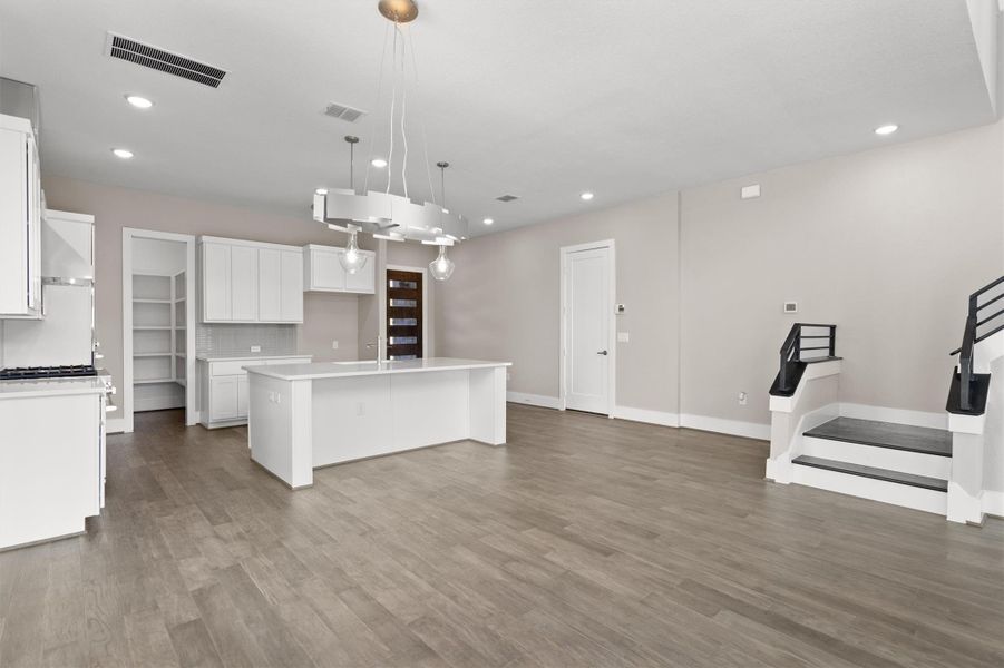 An open concept living area showcases modern lighting, rich flooring, and a kitchen island. An open concept living area showcases modern lighting, rich flooring, and a kitchen island.