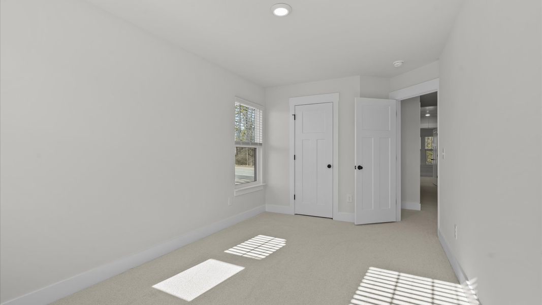 Bright and serene bedroom with comfortable carpeted flooring and large windows for vibrant light