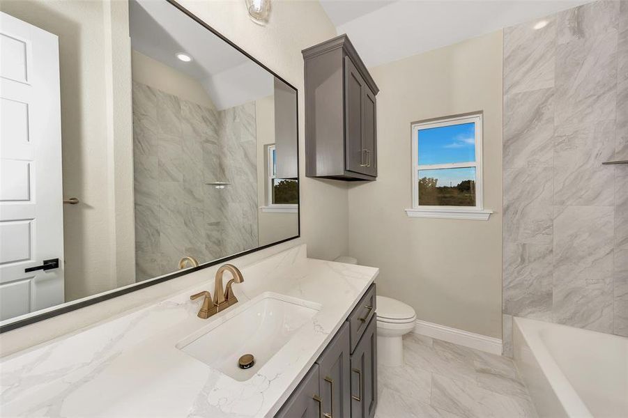 Full bathroom with tiled shower / bath, vanity, and toilet