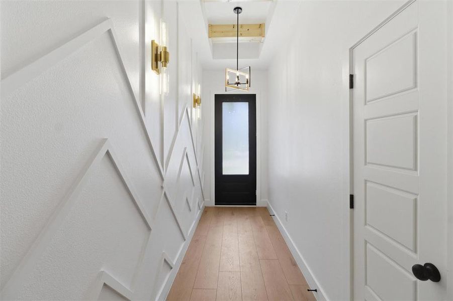 Hallway featuring geometric accent wall paneling and light wood-finish flooring