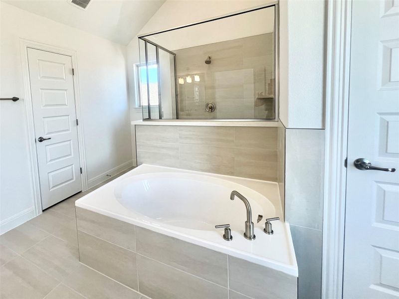 Full bath with lofted ceiling, a bath, tile patterned flooring, and tiled shower