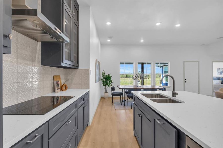 Kitchen with light stone countertops, gray cabinets, light wood-style floors, recessed lighting, and black electric cooktop Kitchen with light stone countertops, gray cabinets, light wood-style floors, recessed lighting, and black electric cooktop