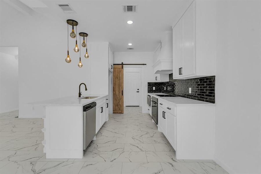 Kitchen featuring light tile patterned flooring, a barn door, custom exhaust hood, and pendant lighting