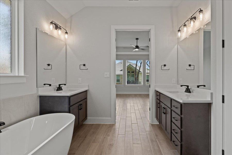 Bathroom featuring a soaking tub, light wood-style floors, two vanities, and a ceiling fan Bathroom featuring a soaking tub, light wood-style floors, two vanities, and a ceiling fan