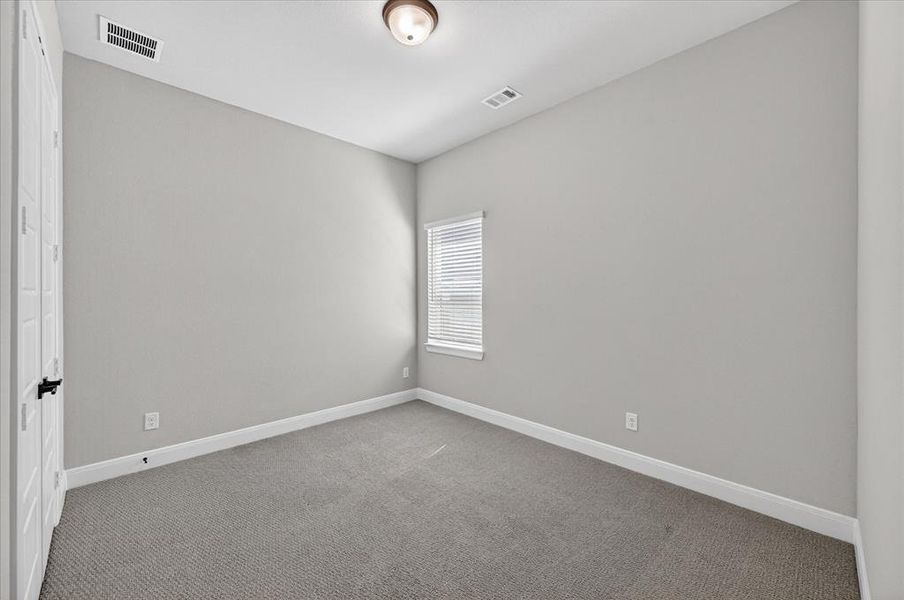 Carpeted room with neutral wall tones and a single window Carpeted room with neutral wall tones and a single window