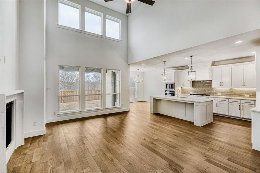 Kitchen featuring white cabinetry, a kitchen island with sink, ceiling fan, decorative backsplash, and open floor plan