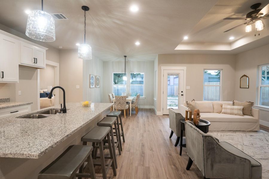 Kitchen with a sink, light wood-style flooring, white cabinets, light stone counters, and recessed lighting