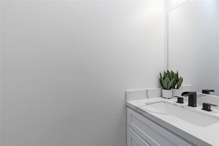 This photo showcases a modern bathroom vanity with sleek fixtures, a wall-mounted mirror, and a decorative plant adding a touch of greenery.