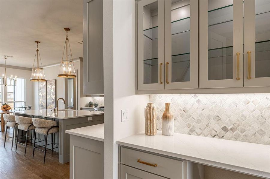 Kitchen with light stone countertops, gray cabinetry, a breakfast bar, crown molding, and backsplash