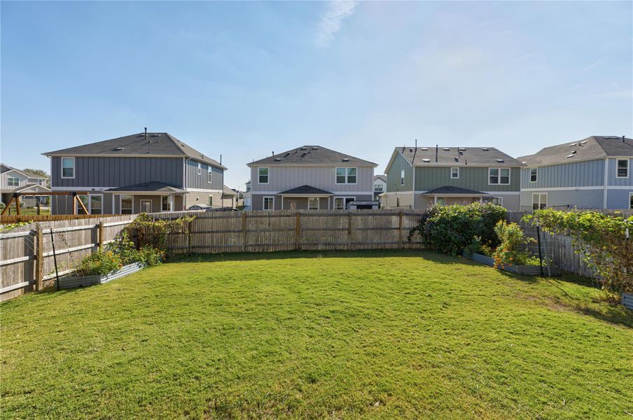 Fenced backyard featuring a garden and a residential view