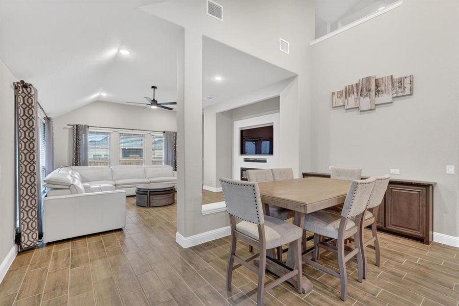Open-concept living and dining areas featuring wood-finish tile flooring, vaulted ceilings with recessed lighting, and a built-in media center Open-concept living and dining areas featuring wood-finish tile flooring, vaulted ceilings with recessed lighting, and a built-in media center