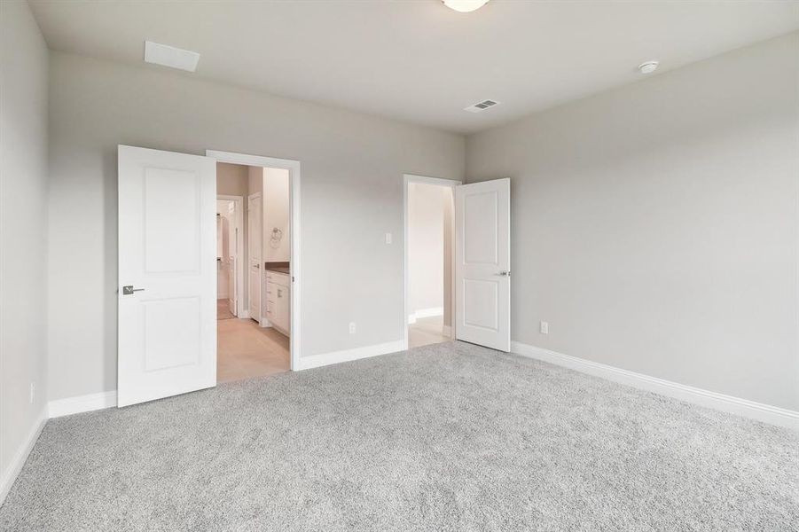 Unfurnished bedroom featuring connected bathroom and light carpet