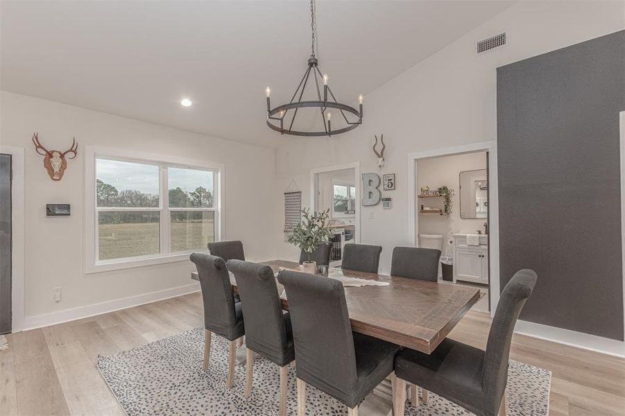 Dining area featuring light wood-style flooring, a chandelier, lofted ceiling, and recessed lighting
