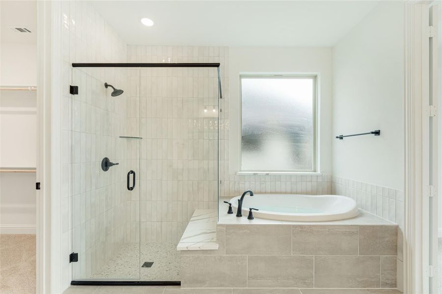 Master bathroom with glass-enclosed tile shower and soaking tub with matte black fixtures