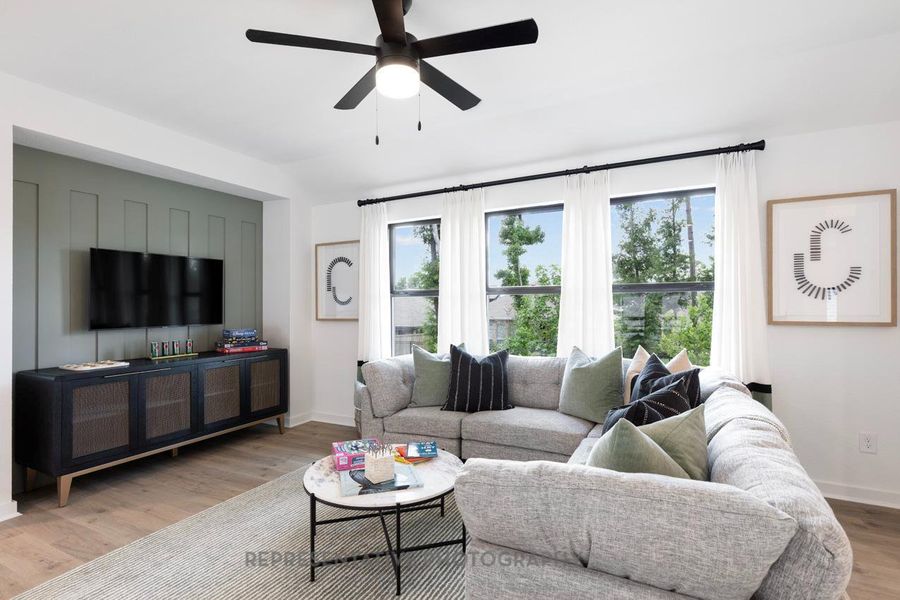 Living area featuring healthy amount of natural light, wood finished floors, and a ceiling fan Living area featuring healthy amount of natural light, wood finished floors, and a ceiling fan