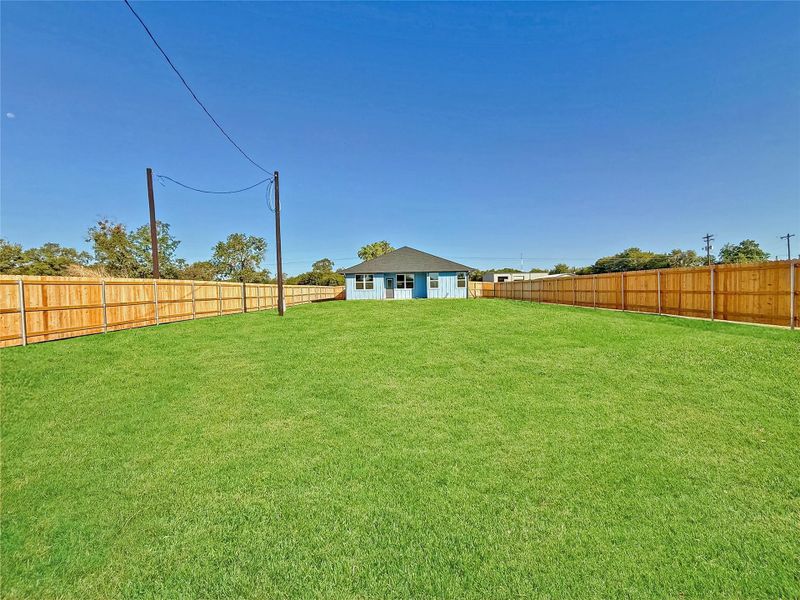Fenced LARGE backyard. This image enhanced by AI to showcase the newly installed carpet grass around house. Please note the carpet grass covers only a portion of the yard, not the entire area.