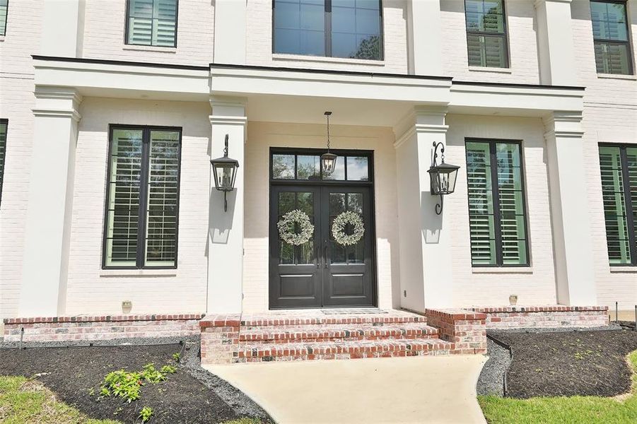 Step up the stairs to the porch. Heavy double doors and stylish light fixtures adorn the outside of the front door!