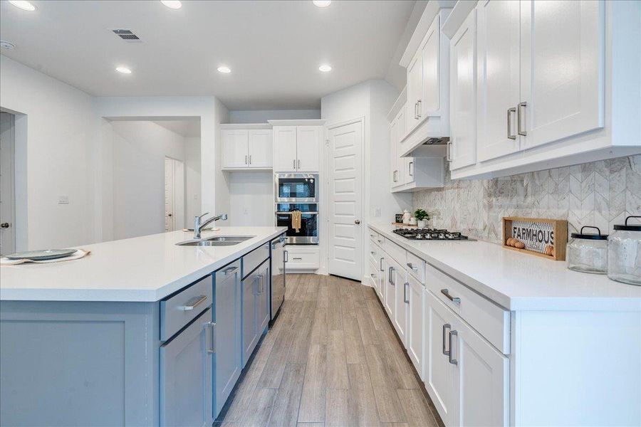 The kitchen features white shaker-style cabinetry, light countertops, a gas cooktop, and a built-in oven