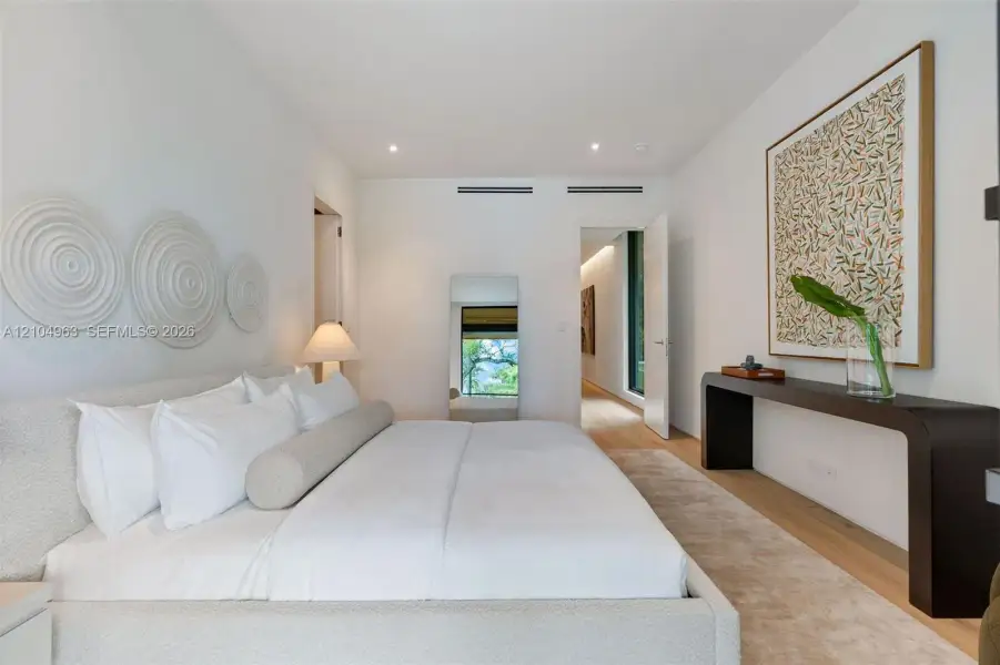Spacious room featuring light-toned wood-finish flooring, recessed ceiling lighting, and smooth white walls