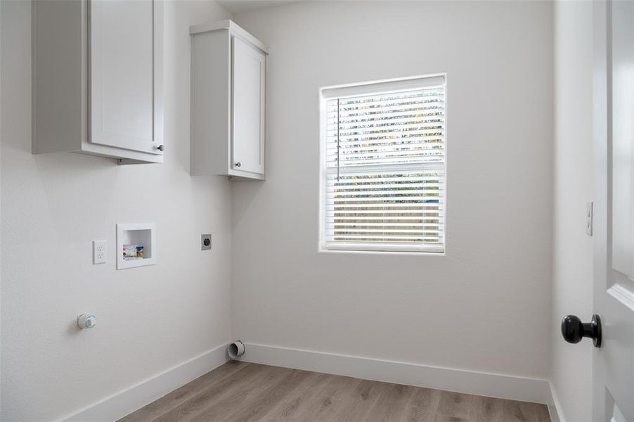 Clothes washing area with electric dryer hookup, light wood-type flooring, cabinets, and hookup for a washing machine