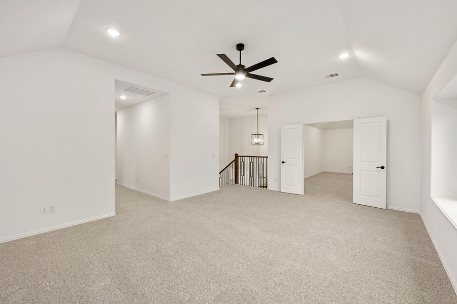 Spacious upstairs bonus room with carpet, ceiling fan, and staircase landing with pendant light Spacious upstairs bonus room with carpet, ceiling fan, and staircase landing with pendant light