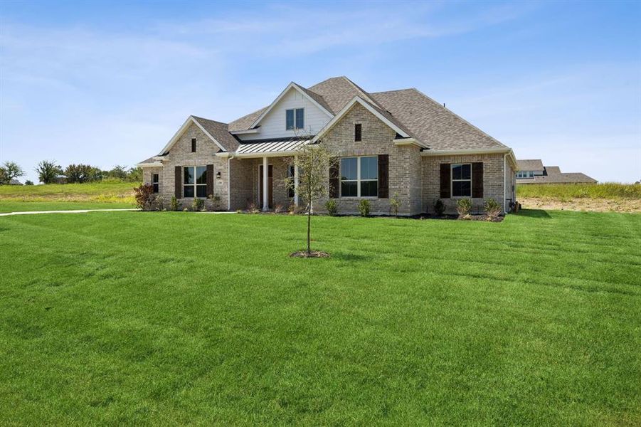 Craftsman inspired home featuring a standing seam roof, a metal roof, a front yard, brick siding, and covered porch
