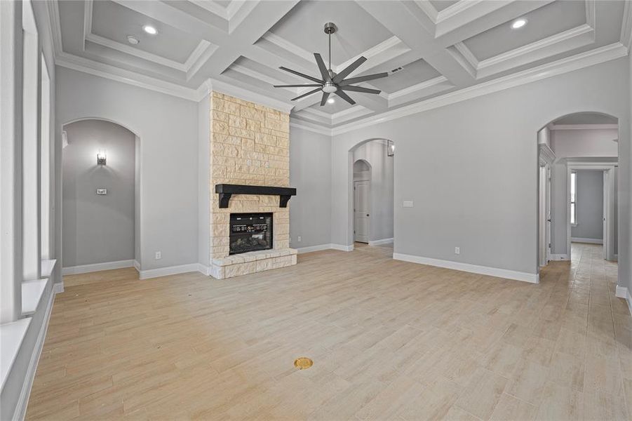 Unfurnished living room with coffered ceiling, a fireplace, and light wood-type flooring