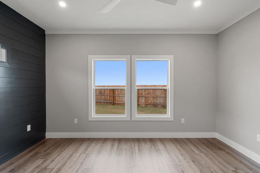 Empty room with light wood-style flooring, a ceiling fan, wood walls, and recessed lighting