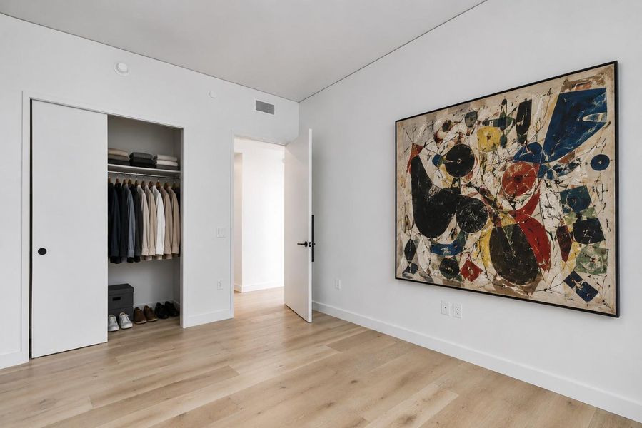 Images shown are virtually staged. Warm hardwood floors and clean gallery-style walls create a minimalist aesthetic in this modern bedroom. Images shown are virtually staged. Warm hardwood floors and clean gallery-style walls create a minimalist aesthetic in this modern bedroom.