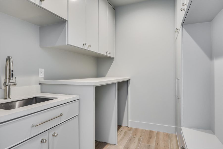 Utility room featuring light-toned cabinetry, a stainless steel sink, and light countertops