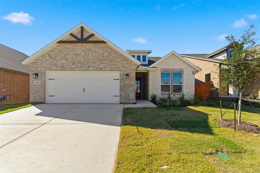Traditional-style house featuring concrete driveway, a front lawn, a garage, and brick siding